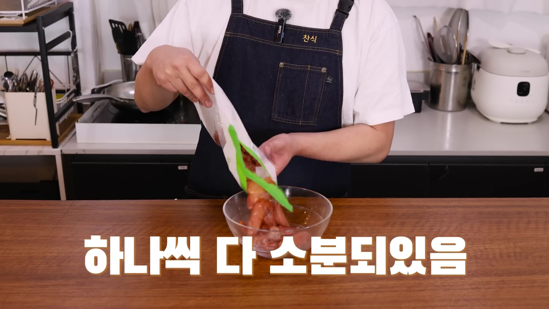 앞치마를 입은 요리사가 냉동 명란이 담긴 포장지에서 내용물을 꺼내 유리 볼에 쏟아 넣고 있는 모습