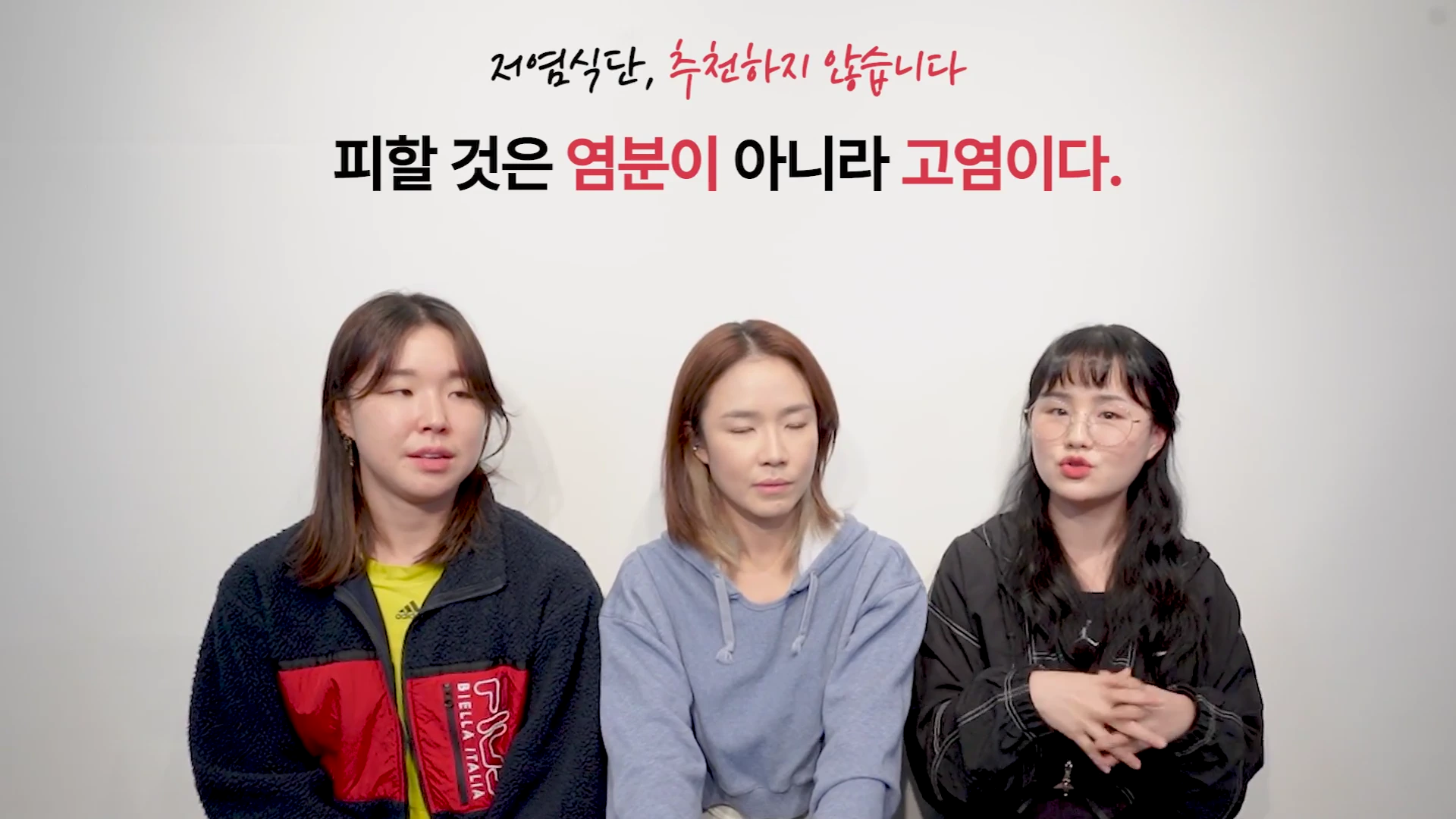 흰색 배경 앞에 세 명의 여성이 나란히 앉아 있고, 화면 상단에는 '저염식단, 추천하지 않습니다. 피할 것은 염분이 아니라 고염이다.'라는 문구가 적힌 영상 캡처 화면입니다.