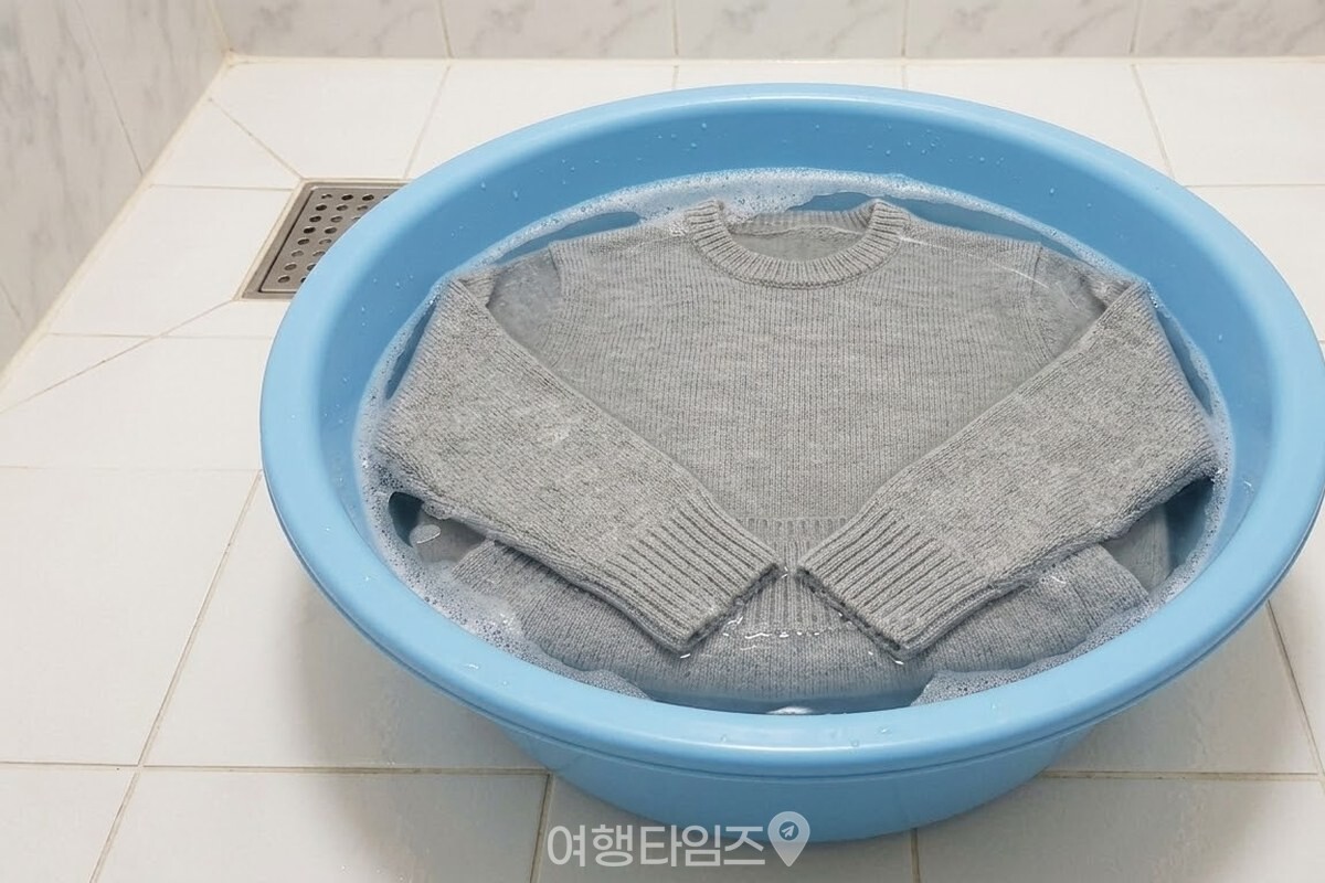 미지근한 물과 거품이 담긴 대야 안에 회색 니트가 소매까지 펼쳐진 채 가라앉아 있다. / 기사 이해를 돕기 위한 생성형 이미지