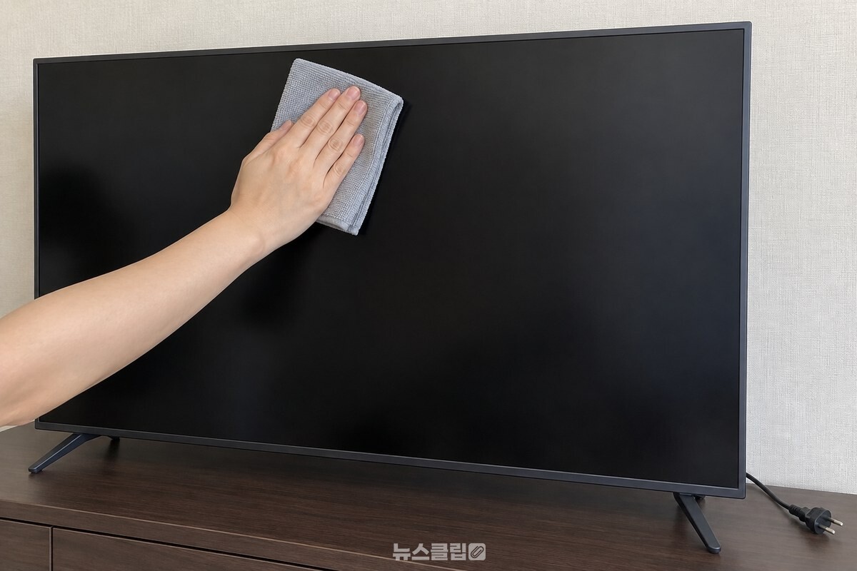 전원을 끈 거실 TV의 검은 화면을 마른 극세사 천으로 위쪽에서 아래쪽으로 쓸어내리는 모습. / 기사 이해를 돕기 위한 생성형 이미지