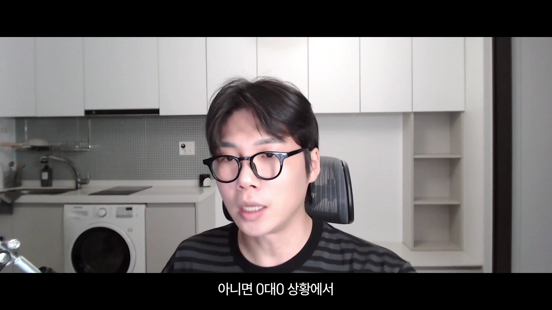 주방을 배경으로 안경을 쓴 남성이 정면을 바라보며 이야기하고 있고 화면 하단에 자막이 표시된 영상 캡처 화면