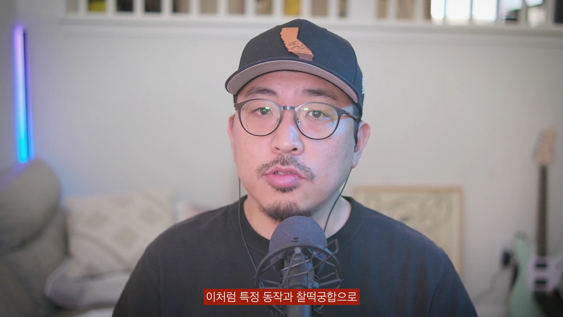 검은색 모자와 안경을 쓴 남성이 마이크 앞에서 정면을 바라보며 이야기하고 있고, 화면 하단에는 한국어 자막이 노란색으로 표시되어 있습니다.