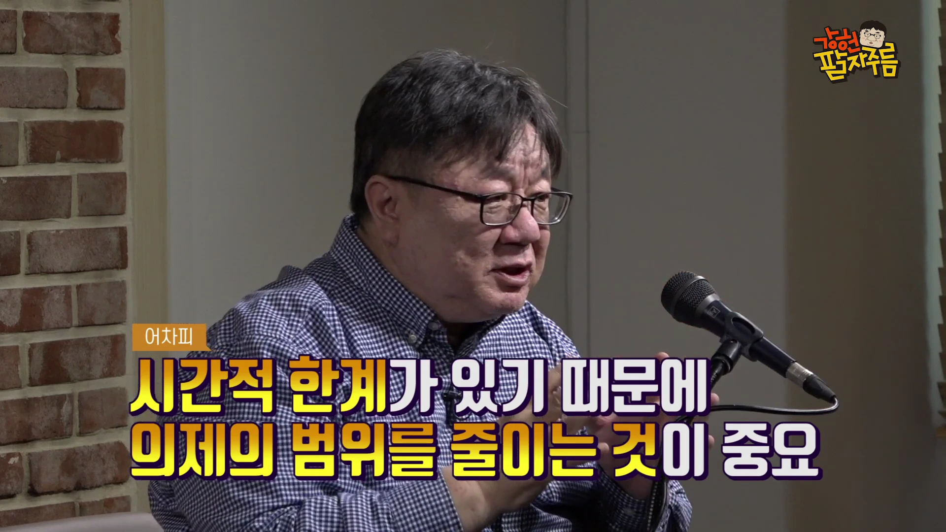 안경을 쓴 중년 남성이 벽돌 벽을 배경으로 마이크 앞에 앉아 손짓하며 대화하는 모습이 담긴 유튜브 영상 화면입니다. 화면 하단에는 자막으로 '어차피 시간적 한계가 있기 때문에 의제의 범위를 줄이는 것이 중요'라는 문구가 강조되어 있습니다.