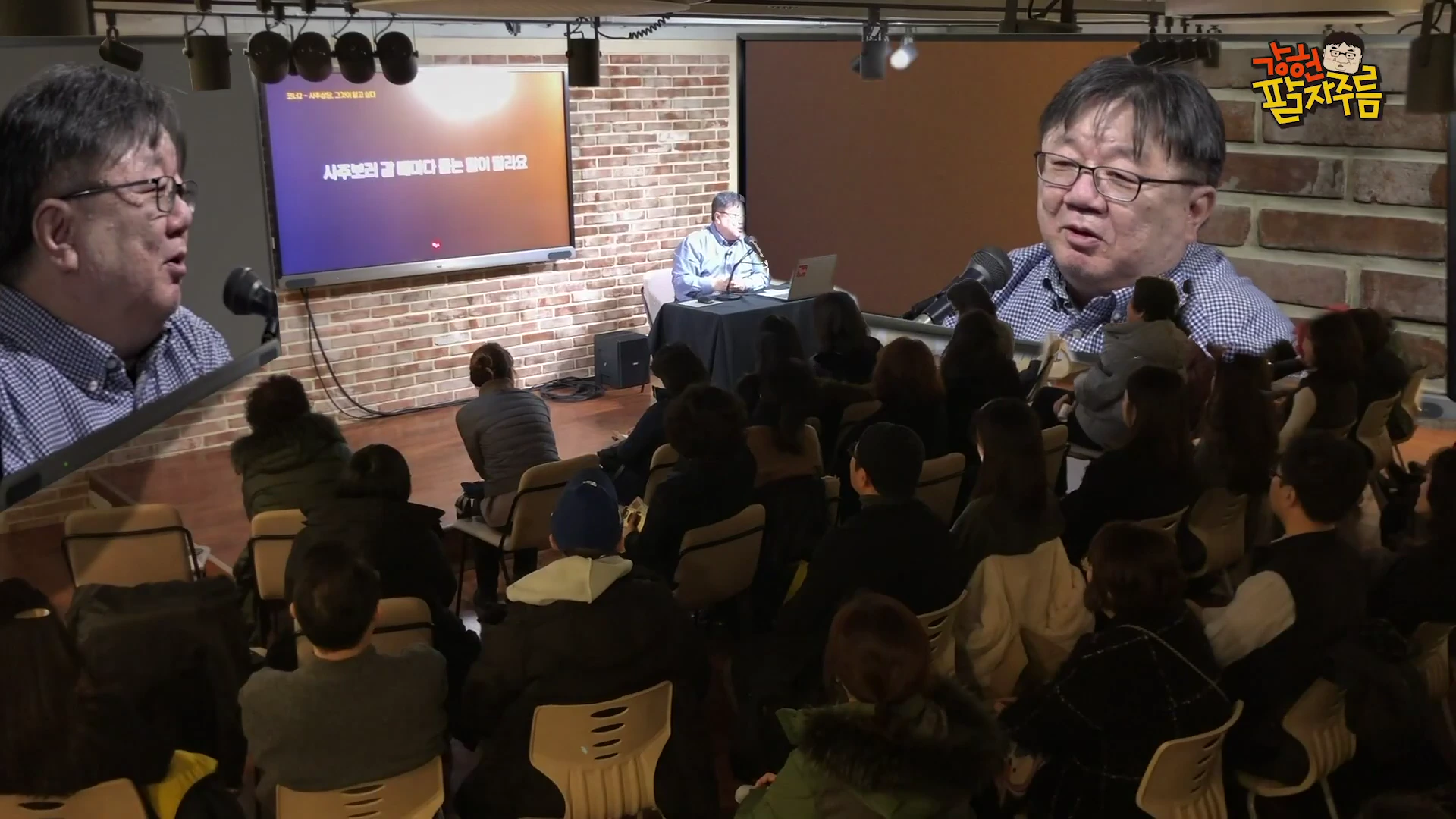 강연장 앞에 앉은 남성이 청중을 향해 이야기하고 있으며, 벽면 대형 화면에는 '사주보러 갈 때마다 듣는 말이 달라요'라는 문구가 적혀 있고, 화면 양옆으로 남성의 모습이 확대되어 보입니다.