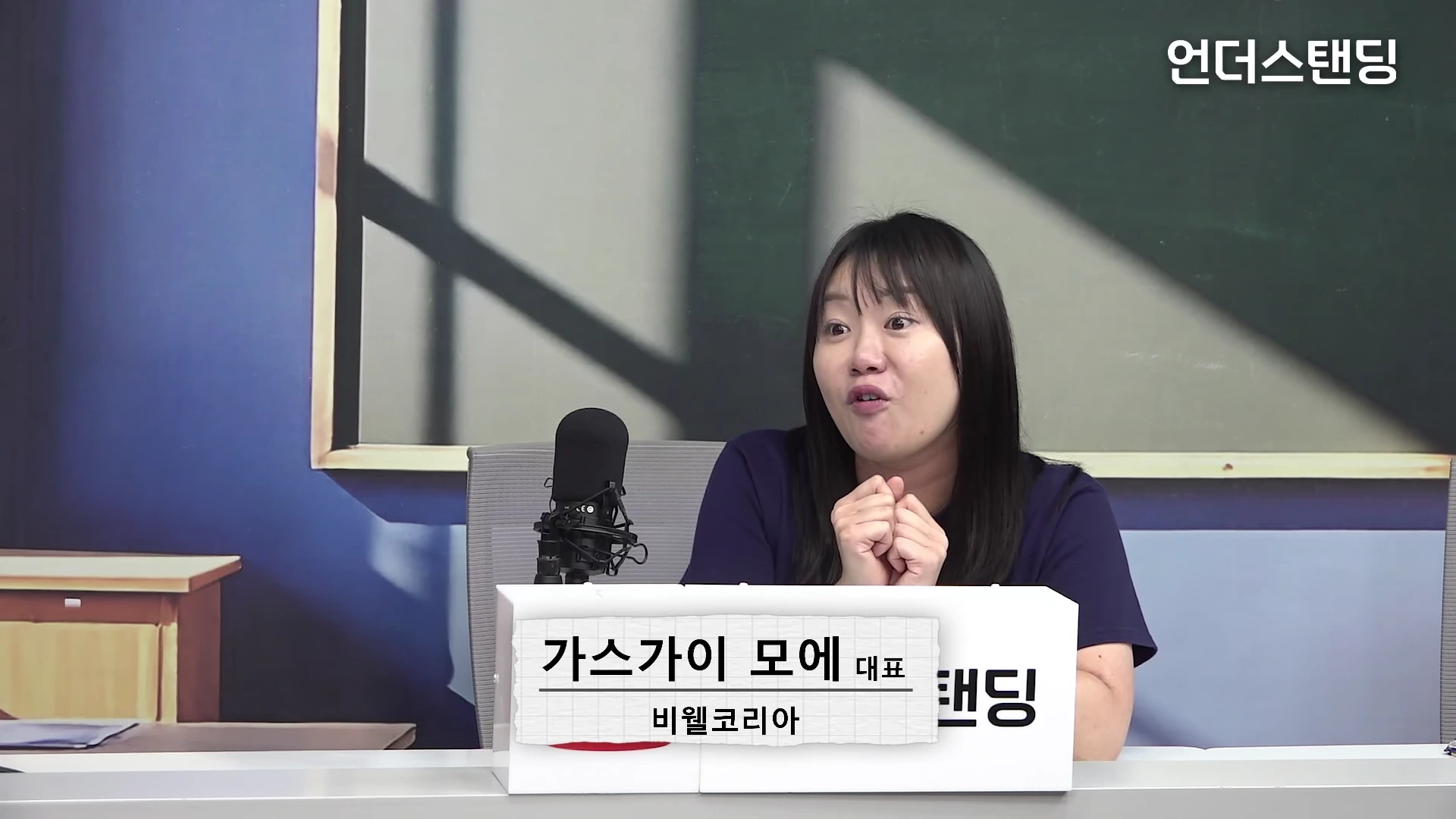한 여성 출연자가 스튜디오 책상 앞에 앉아 이야기하고 있으며, 앞에는 '가스가이 모에 대표'라고 적힌 이름표가 놓여 있습니다.