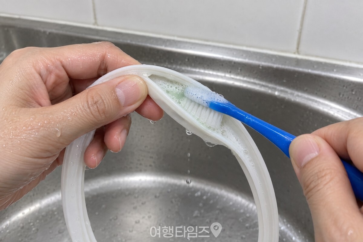 한 손으로 고무 패킹을 펴 잡고 칫솔모를 접힌 안쪽 면에 대어 길이 방향으로 문지르고 있다. / 기사 이해를 돕기 위한 생성형 이미지