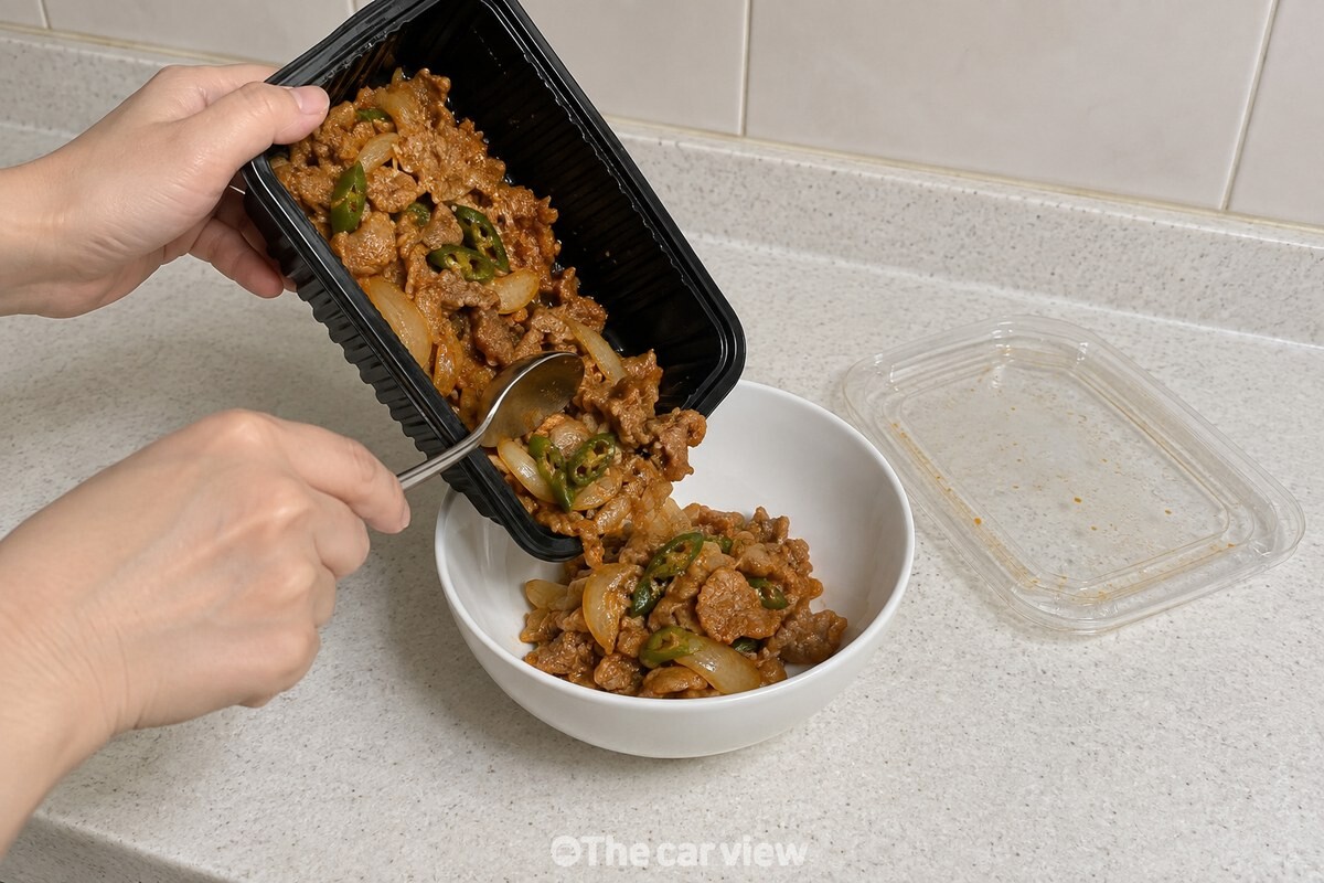 검은 배달 용기에 담겨 있던 볶음 음식을 흰 도자기 그릇으로 옮겨 담고 있고, 투명한 뚜껑은 옆에 따로 빼 두었다. / 기사 이해를 돕기 위한 생성형 이미지