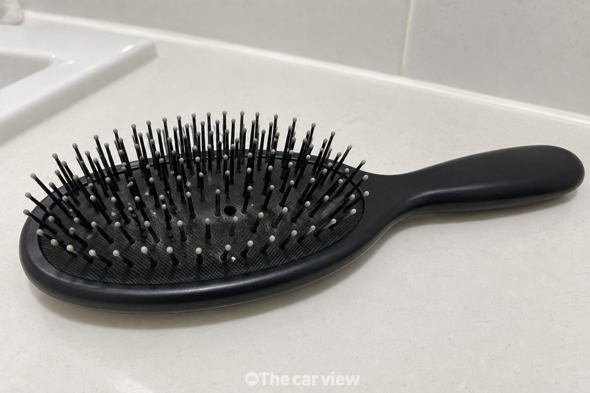 머리카락을 걷어낸 검은 쿠션 브러시를 가까이에서 본 모습으로, 빗살 뿌리 두세 곳에만 옅은 흰 자국이 보인다. / 기사 이해를 돕기 위한 생성형 이미지
