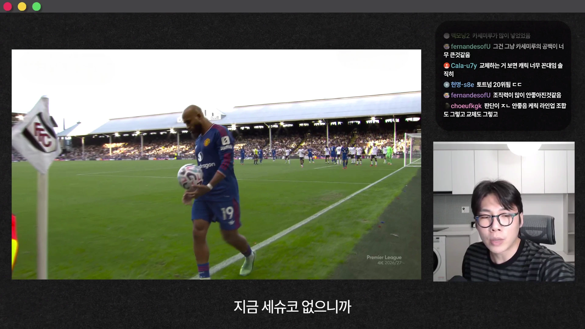 축구 경기 중 코너킥 상황에서 한 선수가 공을 들고 이동하는 모습이 담긴 경기 영상과, 오른쪽 하단에 안경을 쓴 남성이 앉아 있는 모습이 분할 화면으로 구성된 유튜브 영상 캡처.