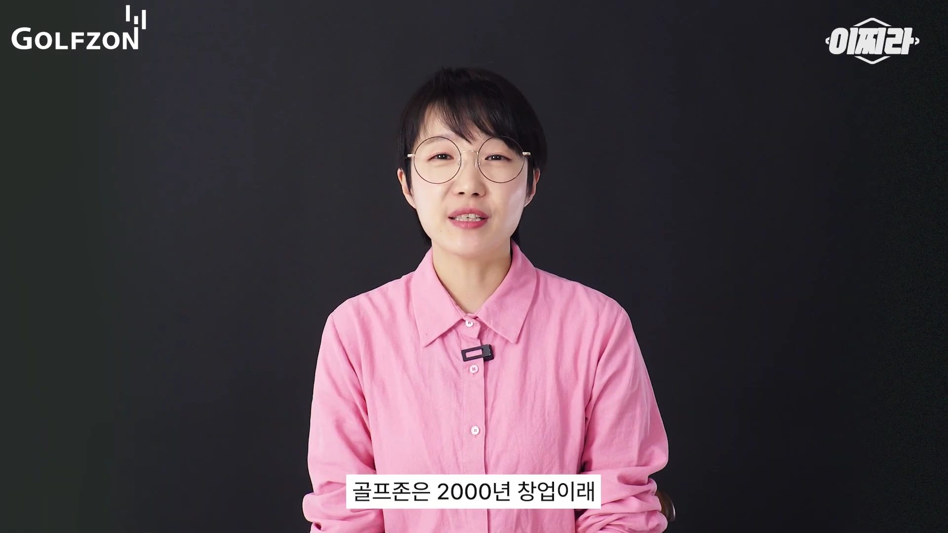 안경을 쓴 단발머리의 여성 출연자가 검은색 배경 앞에서 정면을 바라보며 이야기하고 있다. 화면 상단에는 골프존과 이찌라 로고가 있으며, 하단에는 자막이 표시되어 있다.
