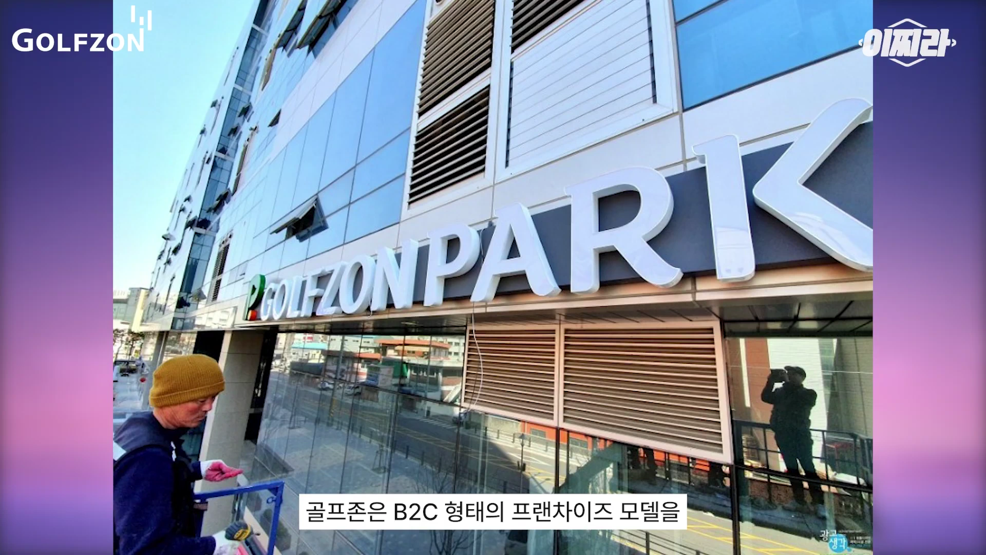 건물 외벽에 설치된 골프존 파크 간판과 그 아래에서 간판 작업을 하는 작업자가 보이는 모습.