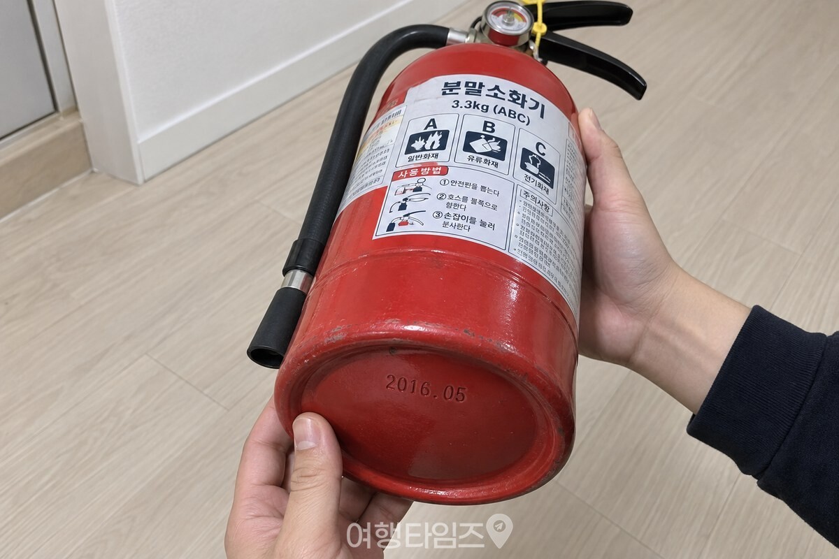소화기를 비스듬히 기울여 바닥 테두리에 찍힌 연·월 표기를 확인하는 모습. / 기사 이해를 돕기 위한 생성형 이미지
