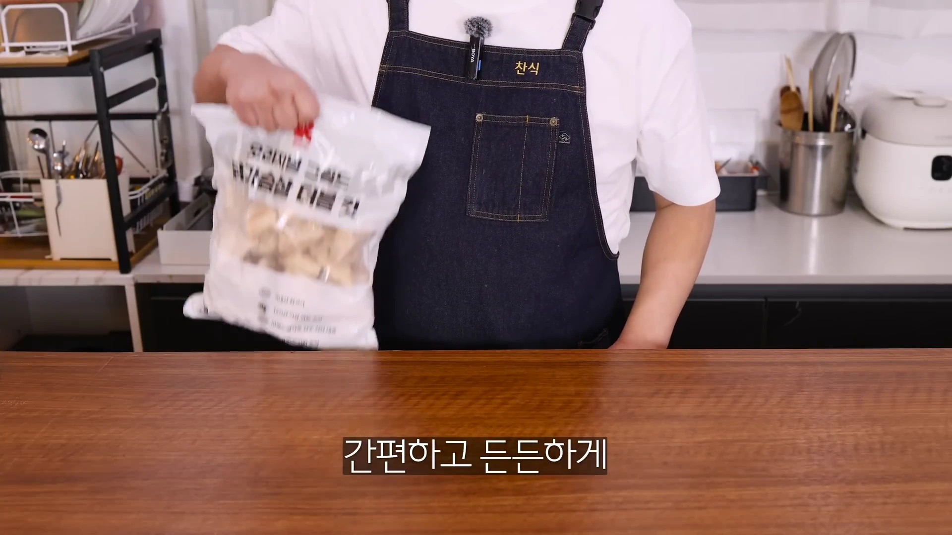 앞치마를 두른 남성이 손에 닭가슴살 대용량 제품 봉지를 들고 있는 모습