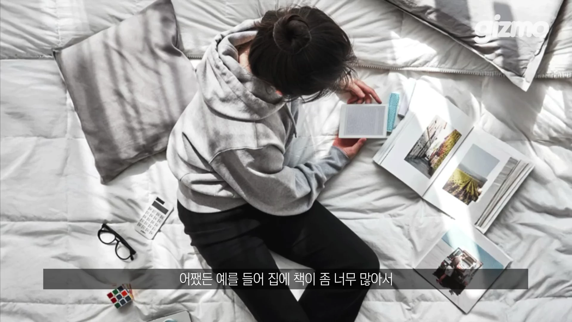 침대 위에 앉아 이북 리더기를 들고 독서 중인 사람의 위에서 내려다본 모습