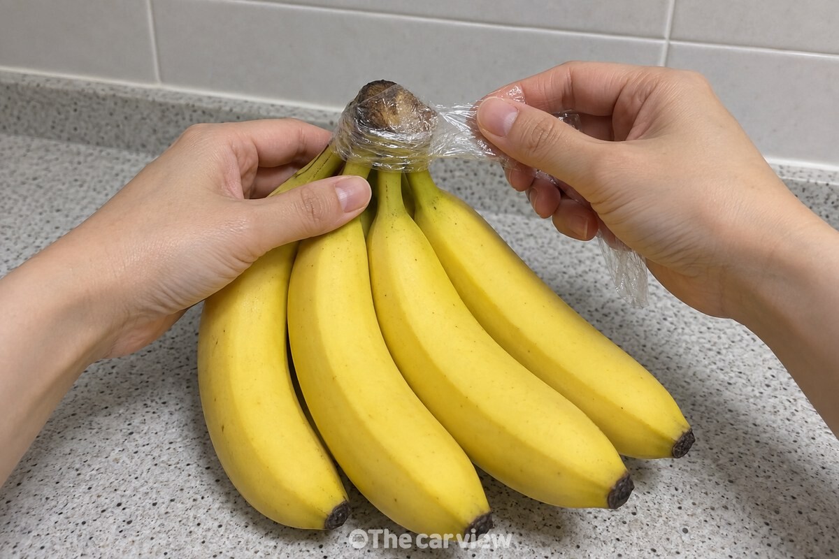 한 손으로 바나나 송이를 잡고 다른 손으로 랩을 꼭지에 둘러 감싸고 있다. / 기사 이해를 돕기 위한 생성형 이미지