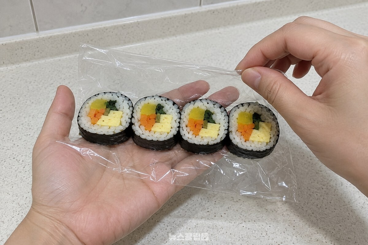 손바닥에 펼친 랩 위에 김밥 네 조각을 나란히 붙여 올린 모습. / 기사 이해를 돕기 위한 생성형 이미지