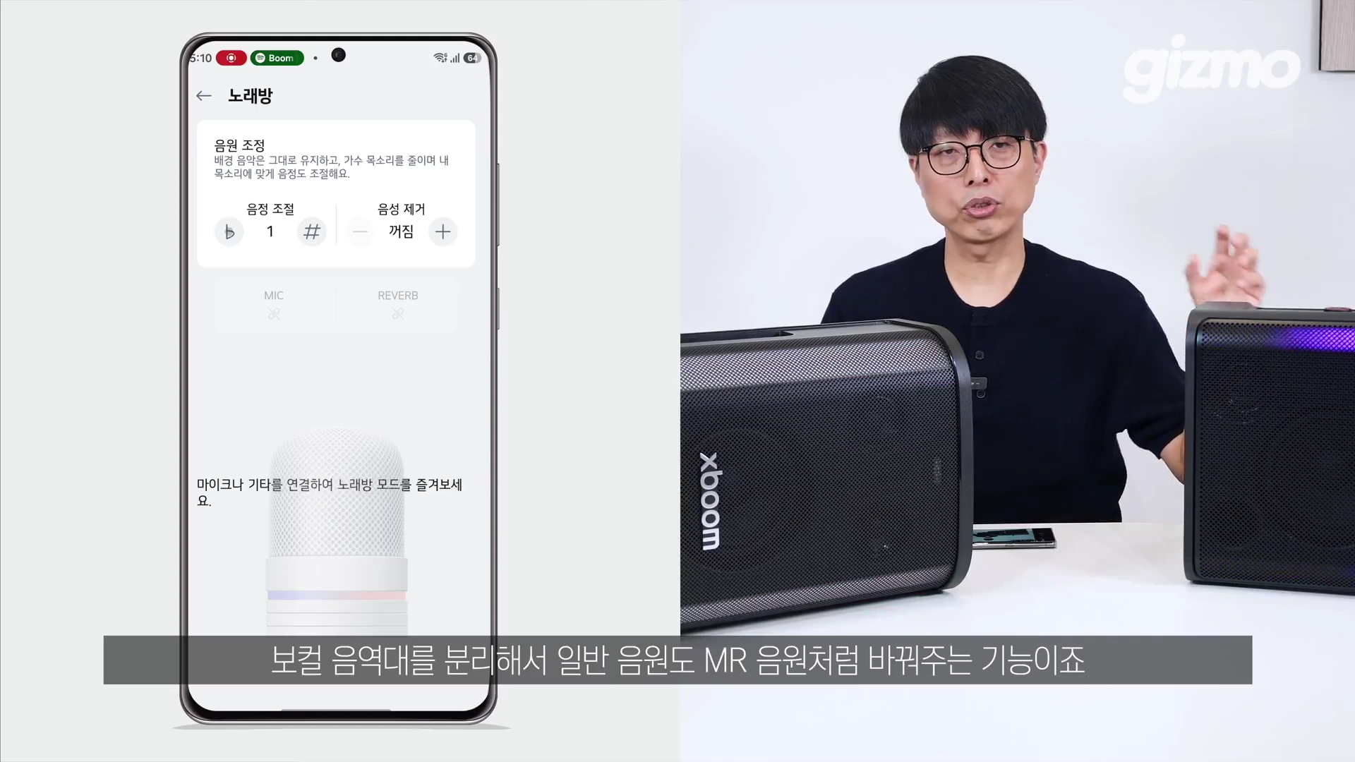 안경을 쓴 남성이 스피커 두 대 옆에서 설명하고 있고 화면 왼쪽에는 '노래방' 메뉴가 떠 있는 스마트폰 앱 인터페이스가 합성되어 있다.