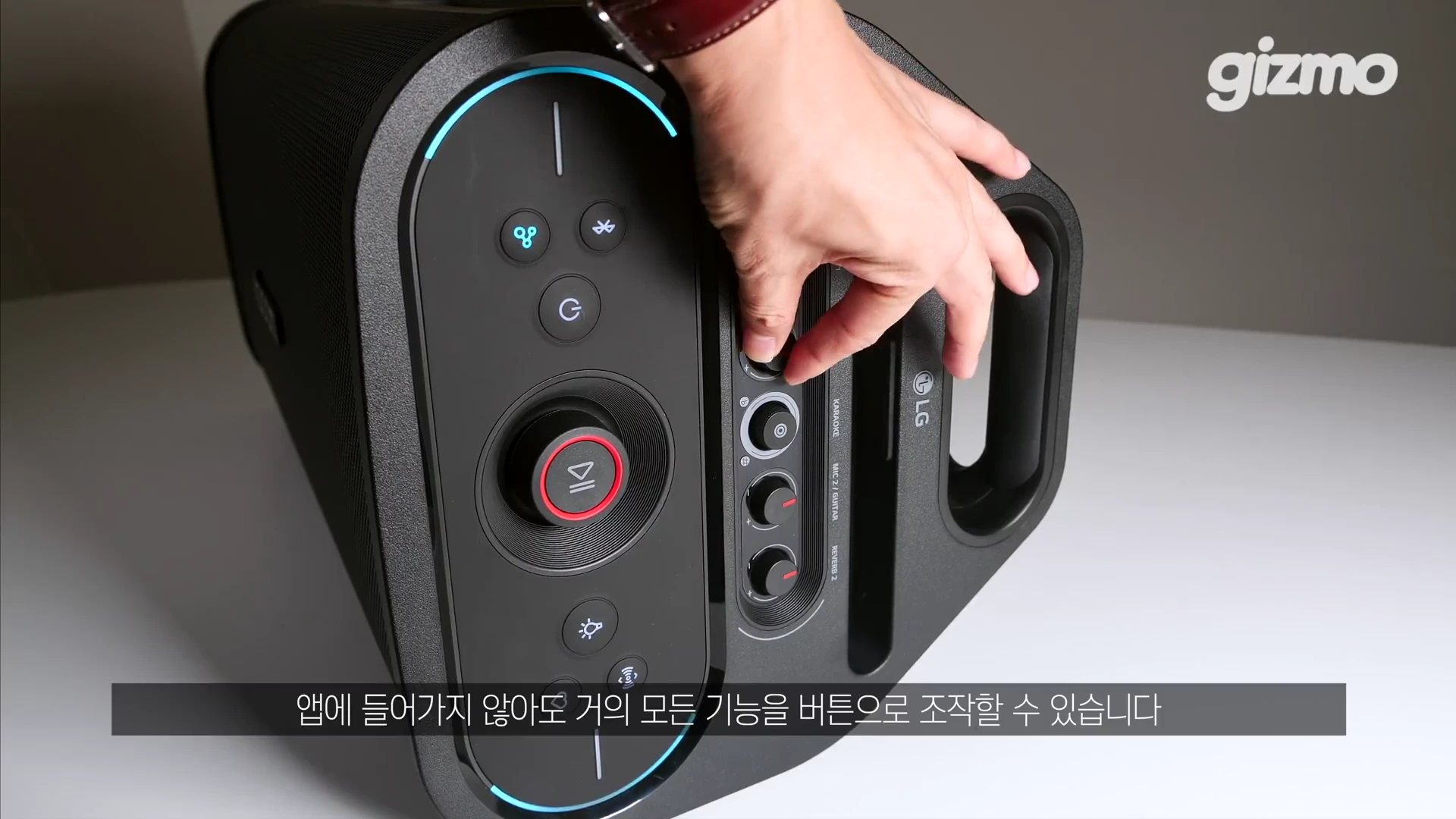 검은색 파티 스피커 상단 조작부를 손으로 조절하는 모습이 담긴 클로즈업 사진이다.