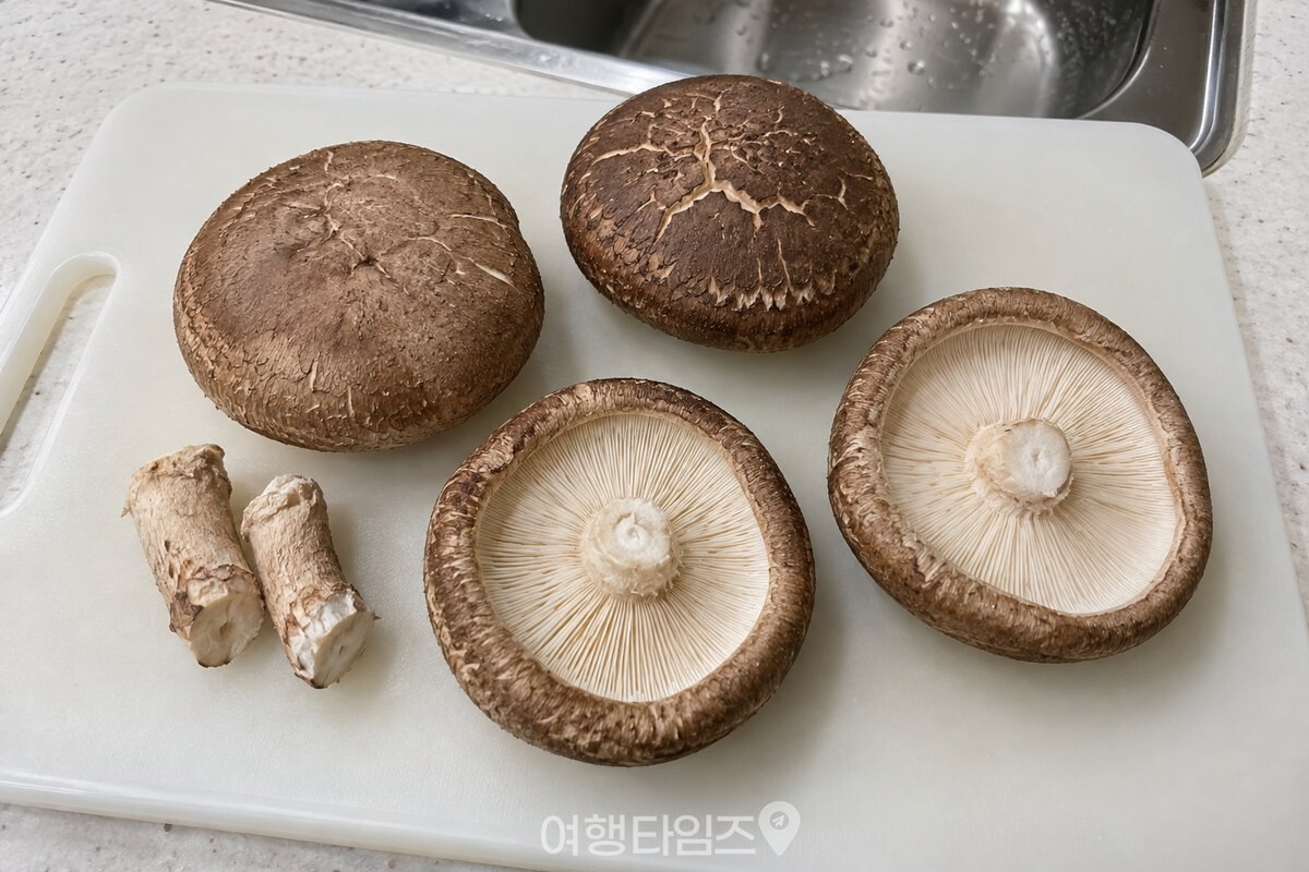 도마 위에 갓이 도톰한 생표고버섯 네 개와 기둥을 떼어 낸 자리가 보이도록 놓여 있다. / 기사 이해를 돕기 위한 생성형 이미지