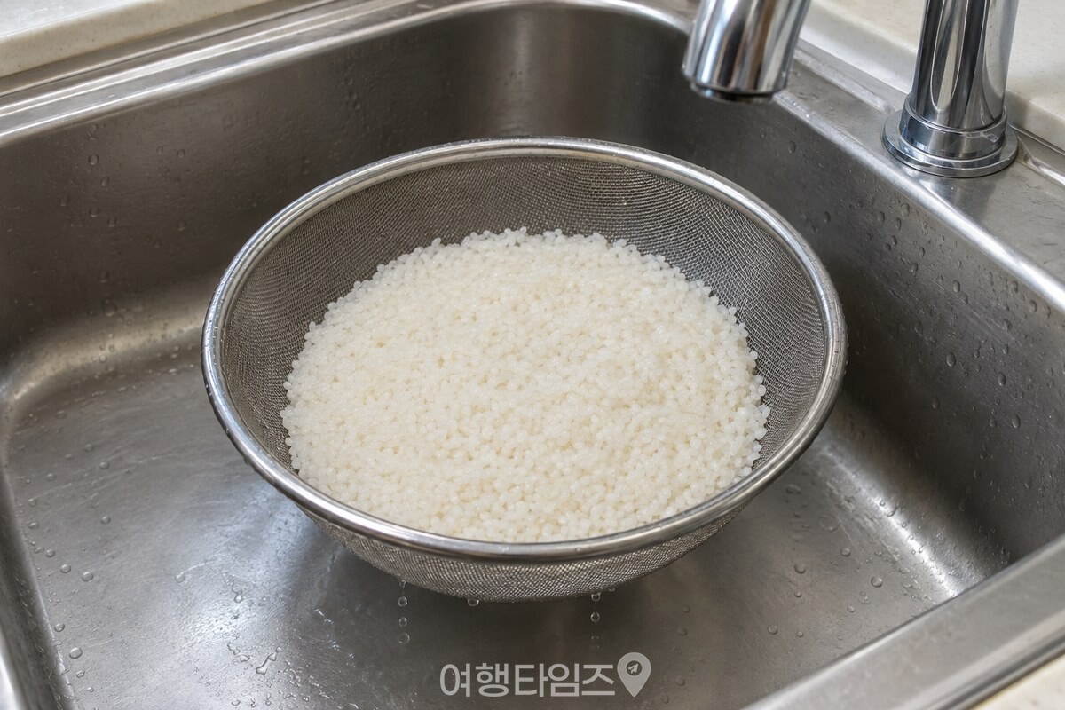 씻은 쌀을 스테인리스 체에 받쳐 싱크대 위에서 물기를 빼는 모습. / 기사 이해를 돕기 위한 생성형 이미지
