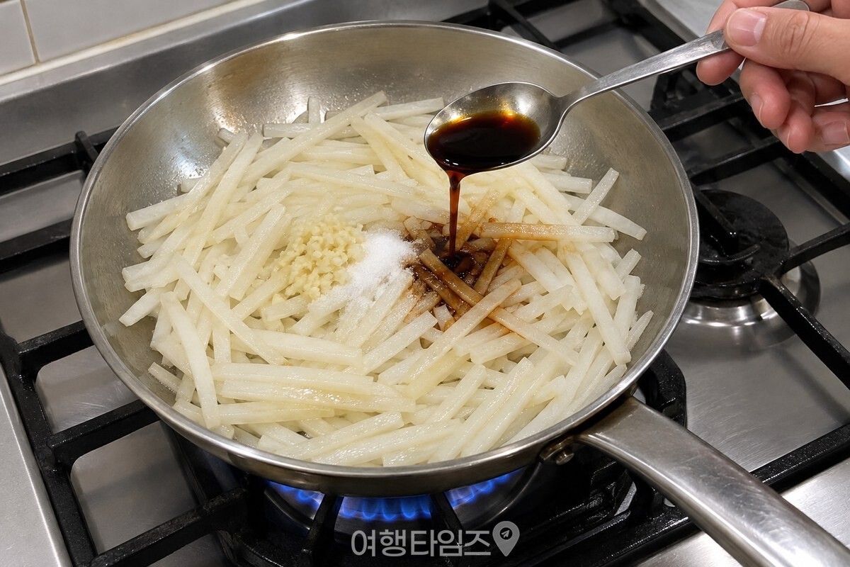 들기름에 볶아 겉이 반들거리는 무채 위로 진간장을 부어 넣는 장면. / 기사 이해를 돕기 위한 생성형 이미지