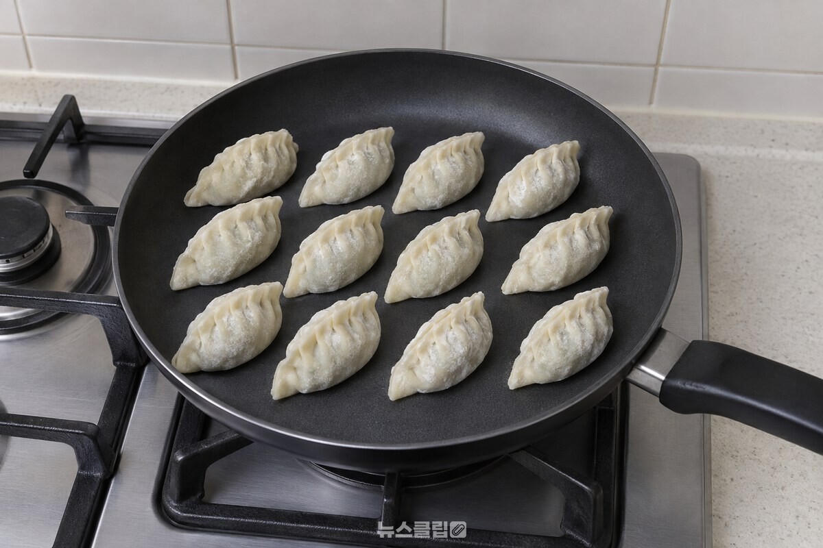 불을 켜지 않은 코팅 프라이팬 바닥에 언 냉동만두를 세 줄로 세워 놓은 모습. / 기사 이해를 돕기 위한 생성형 이미지