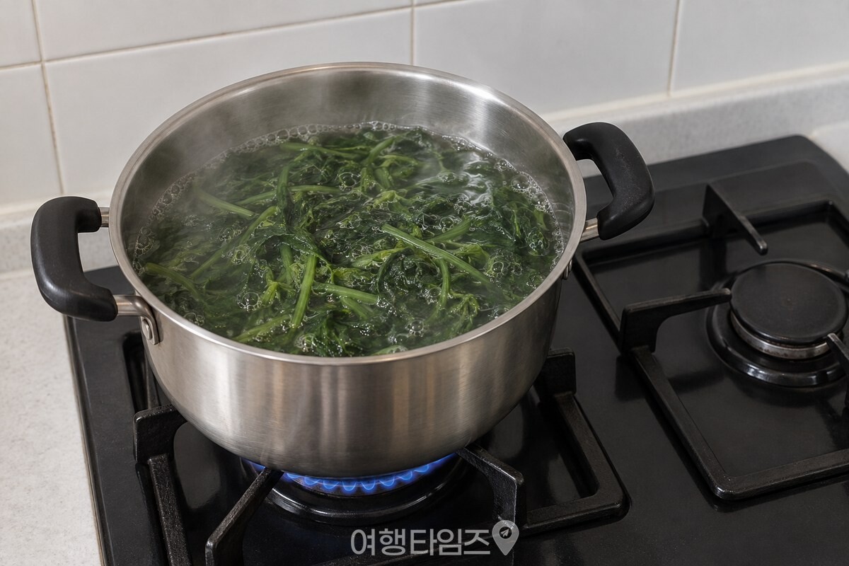 뚜껑을 연 냄비 안에서 취나물이 중간 불로 삶기며 작은 기포가 올라오는 모습. / 기사 이해를 돕기 위한 생성형 이미지