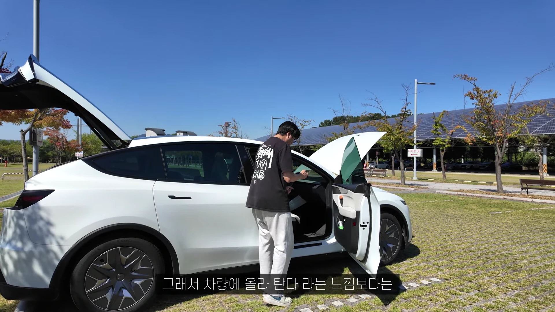 흰색 전기 SUV의 트렁크와 운전석 문을 모두 열어놓고 서 있는 남성의 모습