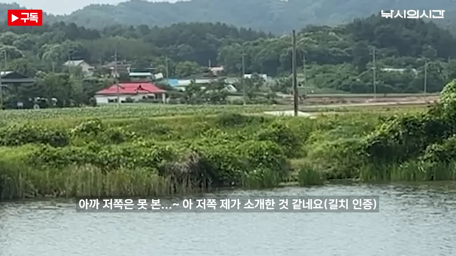 강가 너머로 숲과 마을 건물들이 보이는 풍경으로, 화면 중앙 하단에 한국어 자막이 합성된 영상의 한 장면입니다.