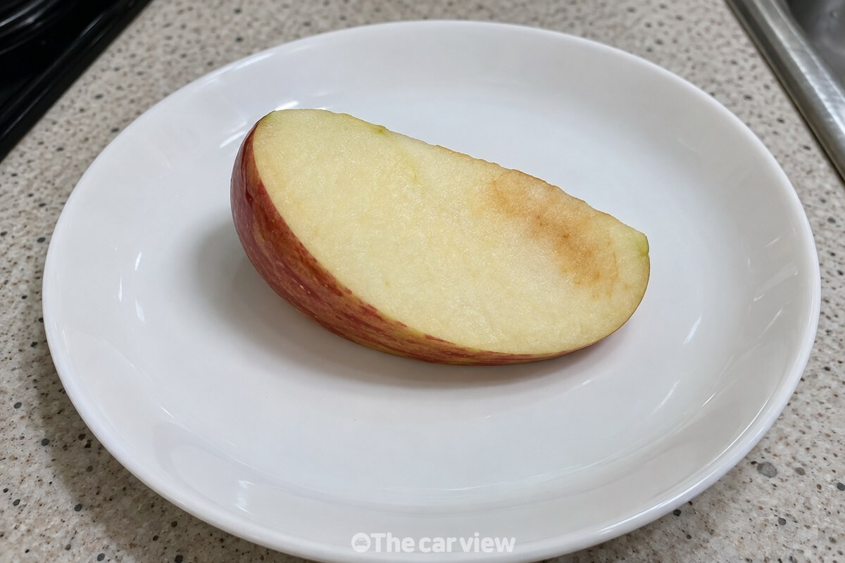 흰 접시 위 사과 조각 한 면에만 옅은 갈색 변화가 보이는 모습. / 기사 이해를 돕기 위한 생성형 이미지