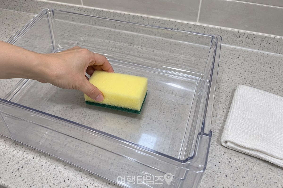 야채칸을 꺼내 바닥에 스펀지를 거친 초록 면이 아래로 가게 평평히 내려놓는 손. / 기사 이해를 돕기 위한 생성형 이미지