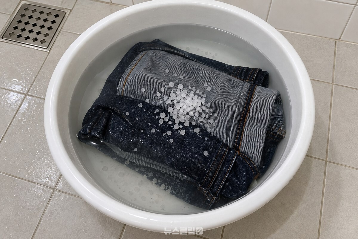찬물을 받은 흰 플라스틱 대야에 굵은소금 한 컵과 뒤집어 접은 진한 청바지를 넣어 담근 모습. / 기사 이해를 돕기 위한 생성형 이미지