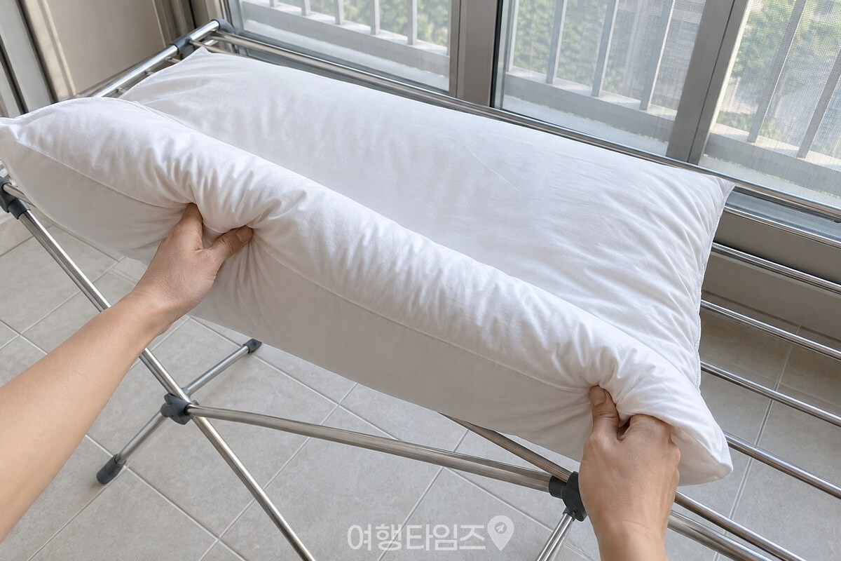 양손으로 베개솜 한쪽 모서리를 들어 건조대 위에서 반대편으로 뒤집는 동작. / 기사 이해를 돕기 위한 생성형 이미지
