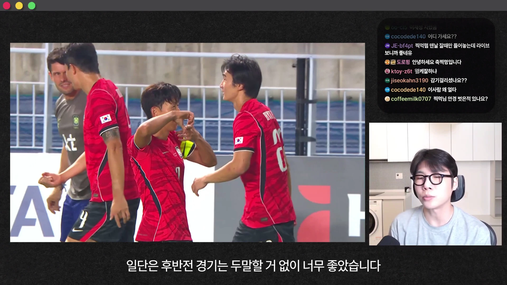 붉은색 축구 국가대표 유니폼을 입은 선수들이 경기장에서 골을 넣은 뒤 기뻐하는 장면이 담긴 영상과, 안경을 쓴 남성이 마이크를 차고 진행하는 모습이 화면에 나타나 있다.