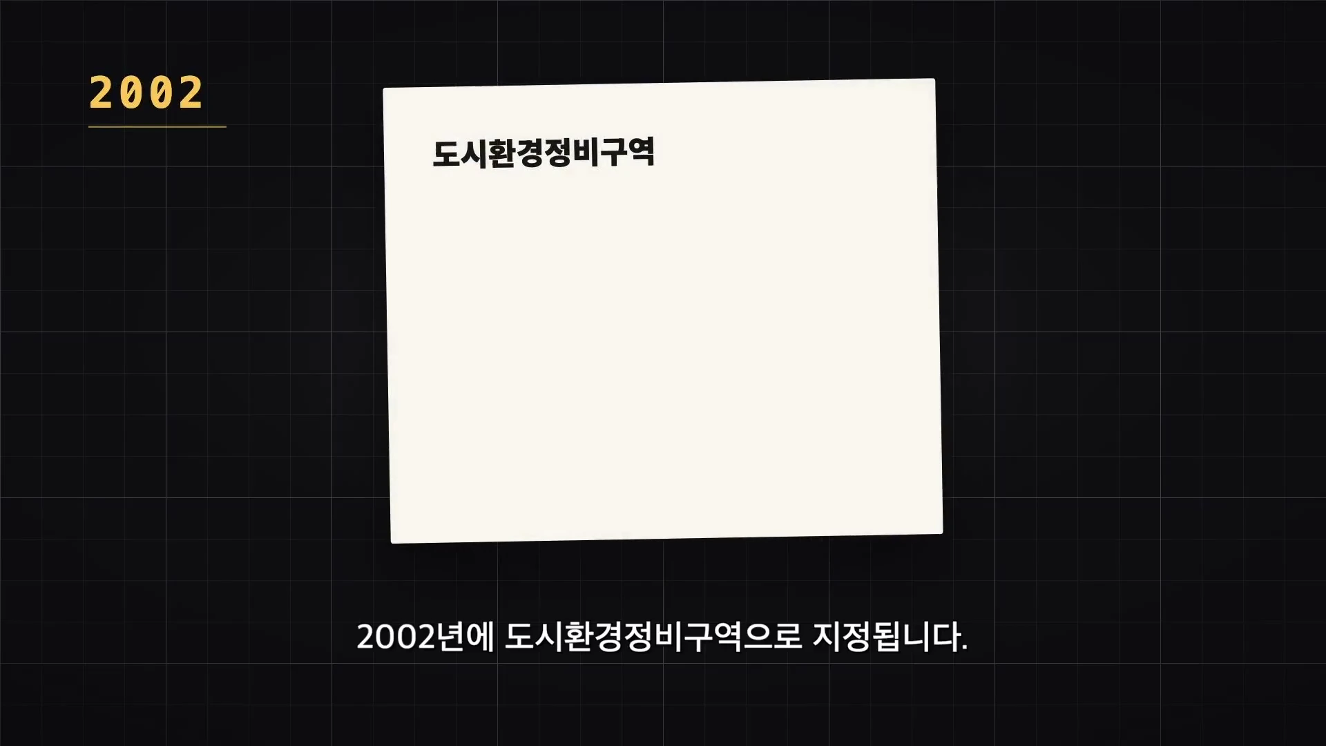 어두운 배경의 그래픽 화면 중앙에 '2002'라는 연도와 '도시환경정비구역'이라는 텍스트가 박스 안에 표시되어 있으며, 하단에는 같은 문구가 자막으로 한 번 더 적혀 있습니다.