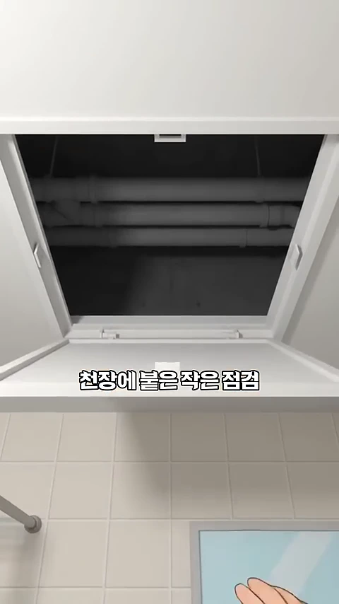 아파트 화장실 천장에 설치된 점검구 뚜껑이 열려 있고, 그 너머 어두운 천장 공간에 수평으로 배치된 여러 개의 굵은 배관들이 보입니다.