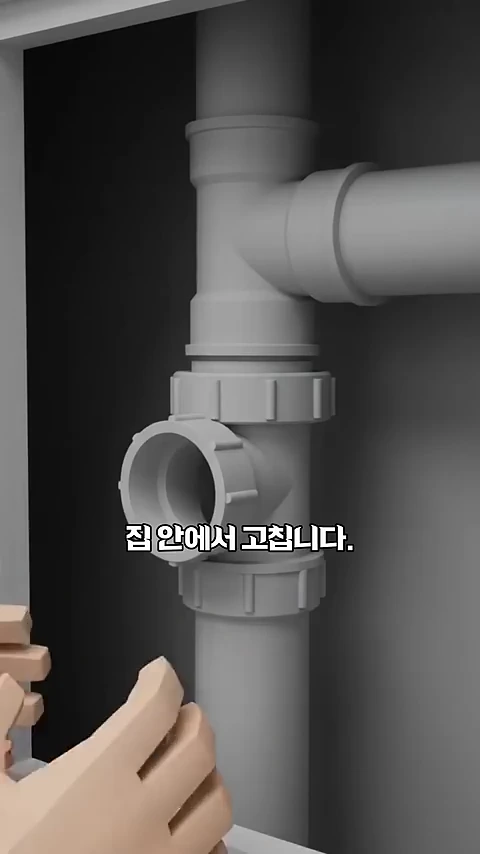 3D 그래픽으로 구현된 화장실 배관 시스템 이미지로, 벽면 뒤에 설치된 수직 배관과 연결된 부품을 사람이 손으로 조절하는 모습이며 '집 안에서 고칩니다.'라는 자막이 적혀 있음.