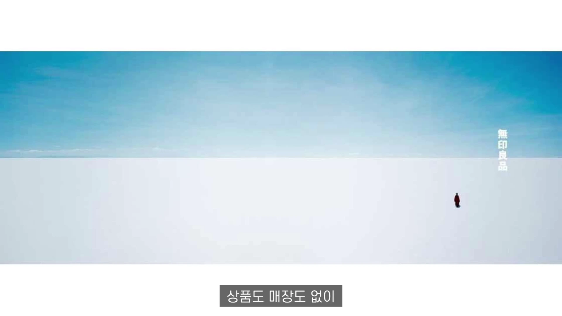 푸른 하늘 아래 끝없이 펼쳐진 하얀 지평선에 작게 서 있는 사람 한 명과 오른쪽 상단에 브랜드 로고가 배치된 광고 영상의 한 장면입니다.