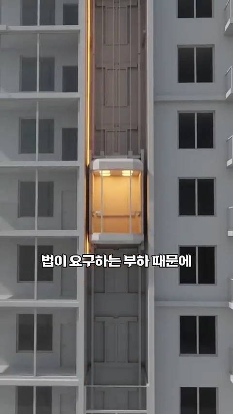 아파트 외벽과 승강기 통로를 수직 단면으로 보여주는 3D 그래픽 영상으로 '법이 요구하는 부하 때문에'라는 자막이 중앙에 표시되어 있다.