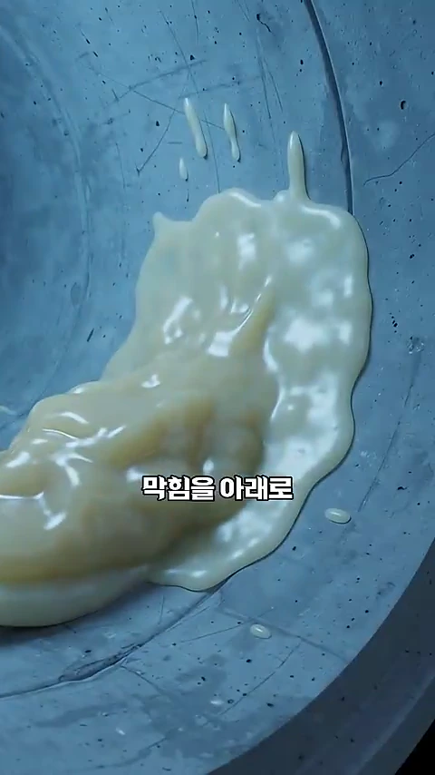차갑고 매끄러운 회색 하수관 벽면에 걸쭉하고 노란색을 띠는 기름 덩어리가 흘러내리며 달라붙어 있는 모습을 보여주는 영상 화면이다.