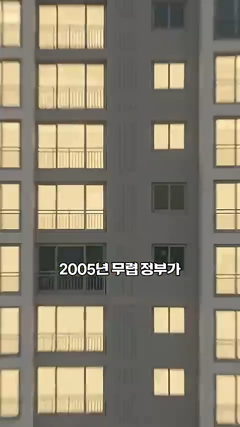 저녁 무렵 불이 켜진 아파트의 외벽 전경. 여러 층의 창문이 나란히 보이며 중앙에 2005년 무렵 정부가라는 자막이 입혀져 있다.