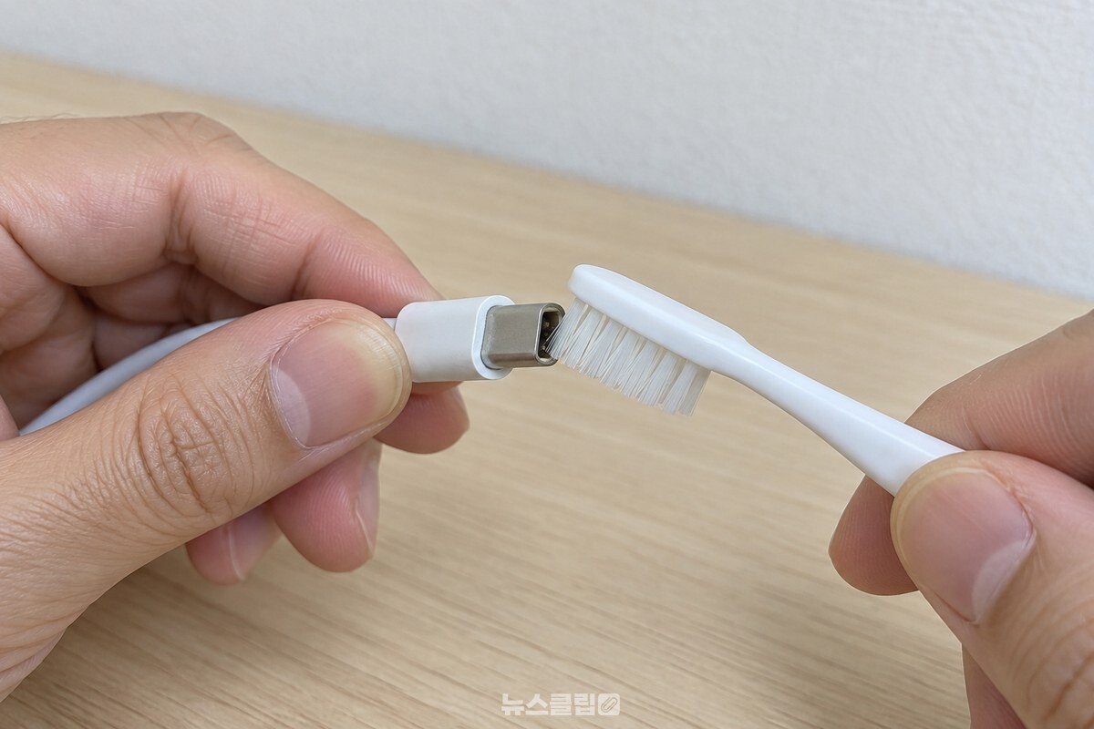 전원을 뺀 USB-C 케이블 끝을 마른 칫솔로 조심스럽게 털어 내는 모습. / 기사 이해를 돕기 위한 생성형 이미지