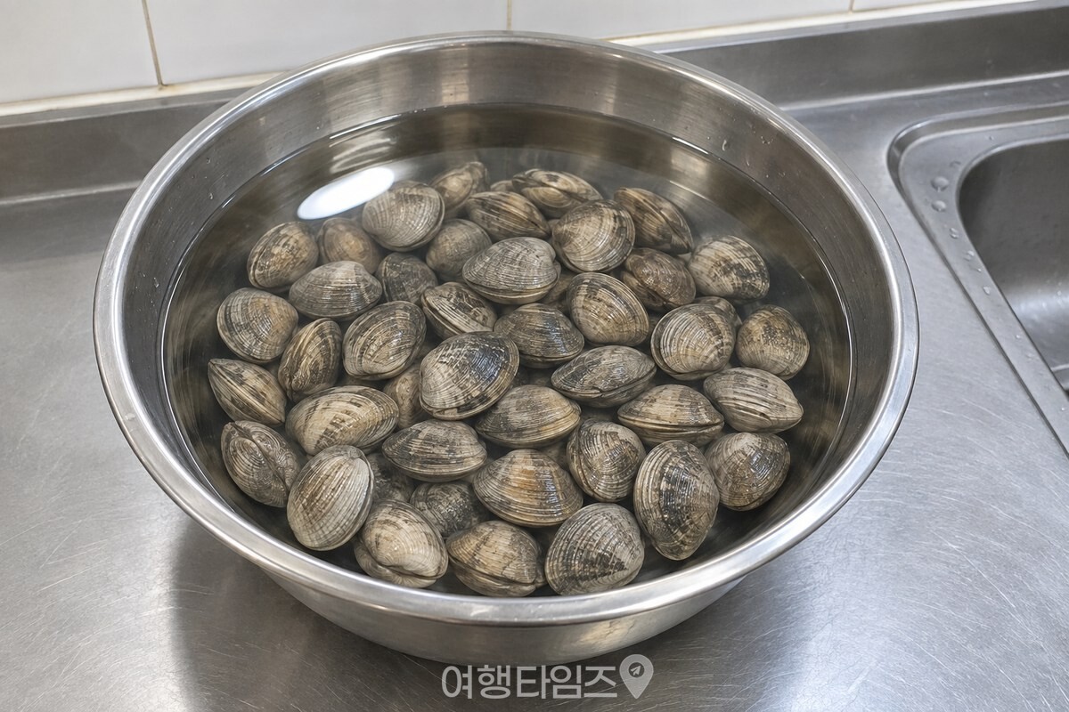주방 조명 아래 덮개 없이 놓인 대야 속에서 껍데기를 꽉 다문 바지락. / 기사 이해를 돕기 위한 생성형 이미지