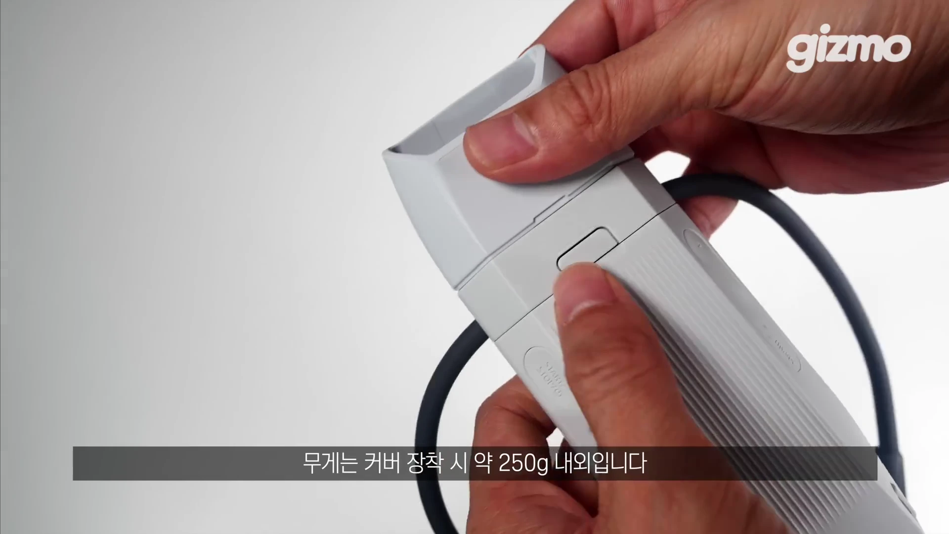 두 손으로 흰색 플라스틱 소재의 웨어러블 장치에 커버를 장착하는 모습