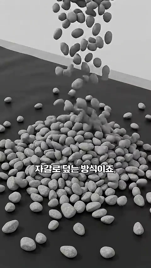회색 자갈들이 검은색 평평한 바닥 위로 쏟아져 내려 쌓이고 있는 애니메이션 영상 화면