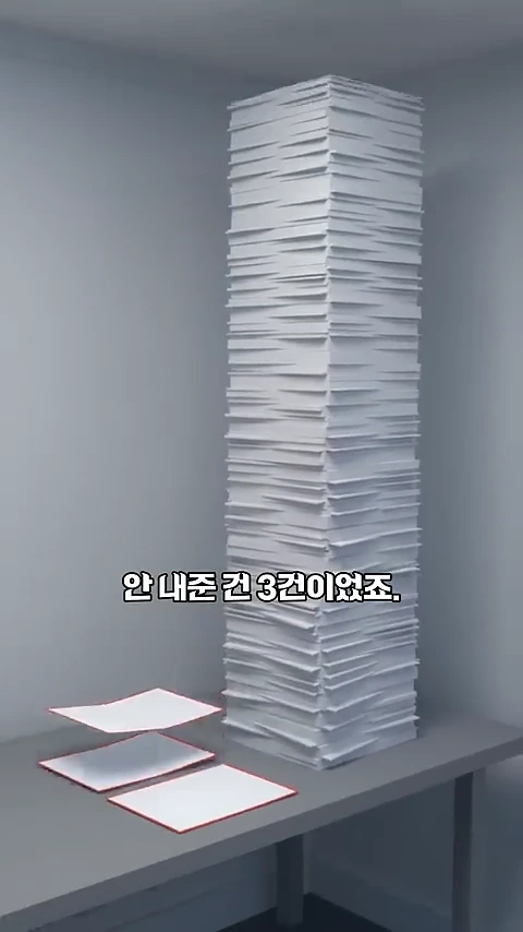 탁자 위에 아주 높게 쌓여 있는 수많은 종이 더미와 그 옆에 나란히 놓인 세 장의 종이가 보이며, 화면 중앙에 '안 내준 건 3건이었죠.'라는 문구가 적혀 있다.