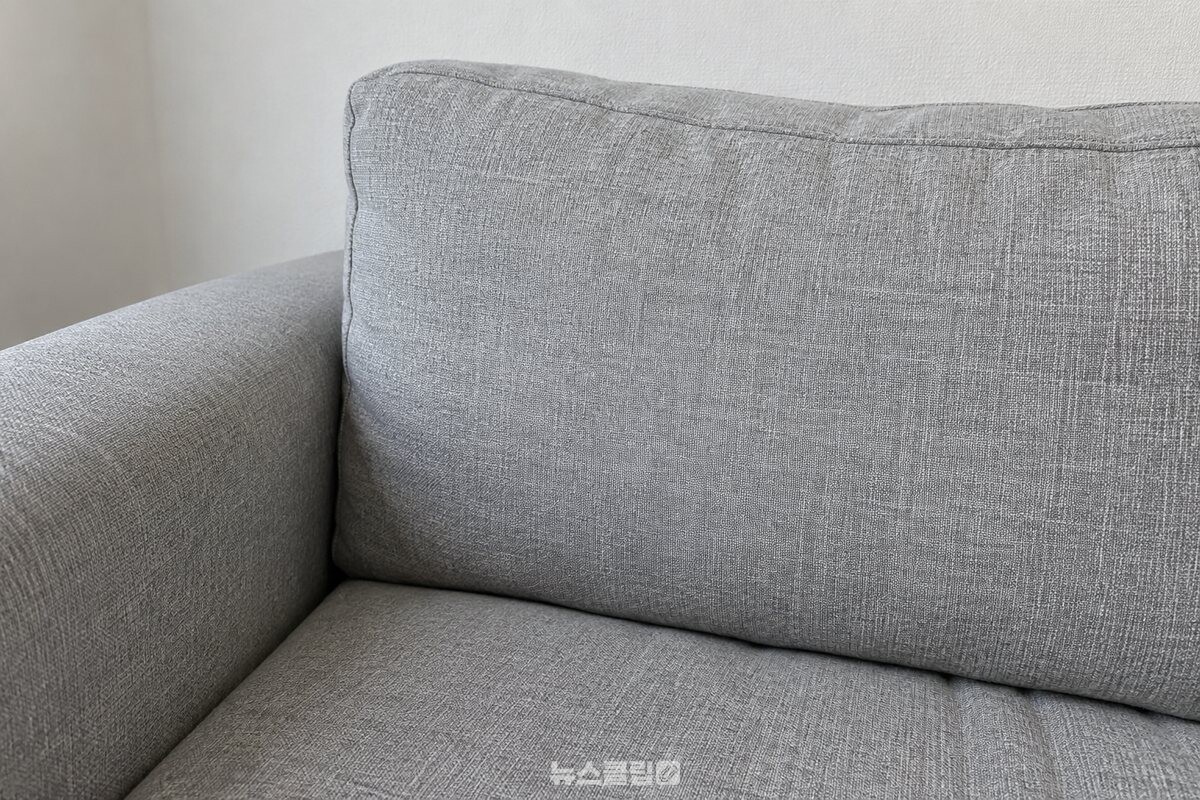 천 소파 등받이 쿠션의 촘촘한 직물 결을 비스듬히 가까이에서 보여 주는 모습 / 기사 이해를 돕기 위한 생성형 이미지