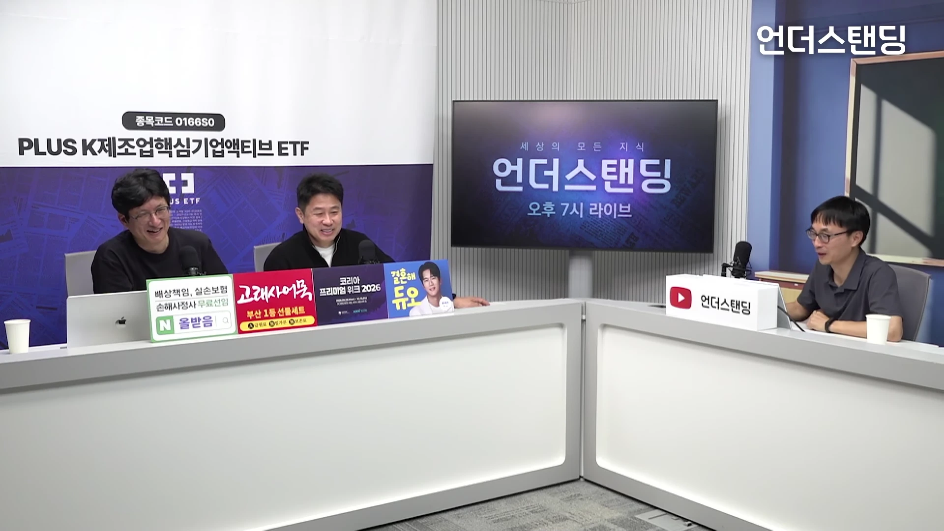 밝은 스튜디오에서 세 명의 남성이 책상에 앉아 대화를 나누는 모습. 왼쪽에는 두 명이, 오른쪽에는 한 명이 앉아 있으며 각자 앞에 마이크가 놓여 있고 배경에는 채널명이 적힌 대형 화면이 설치되어 있다.