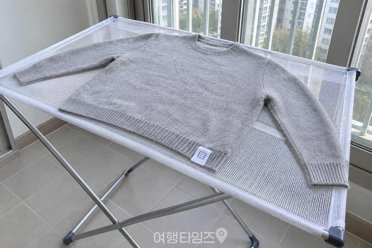 건조망 위에 평평하게 펼쳐 말리는 니트 소매와 가로줄 건조 기호 라벨. / 기사 이해를 돕기 위한 생성형 이미지