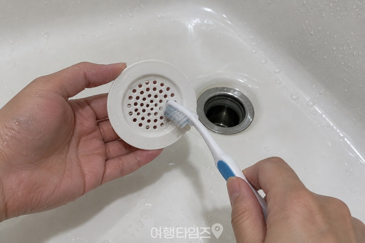 욕조 배수구의 거름망을 꺼내 칫솔로 구멍을 닦는 모습. / 기사 이해를 돕기 위한 생성형 이미지